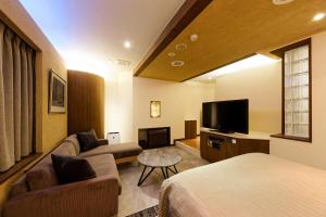 a hotel room with a couch and a tv at Hotel NOON in Kawaguchi