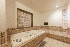 a large bathroom with a tub and a window at Hotel NOON in Kawaguchi