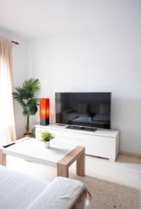 ein Wohnzimmer mit einem großen TV an einer weißen Wand in der Unterkunft APARTAMENTO LOS BATELES - Frente a la playa in Conil de la Frontera