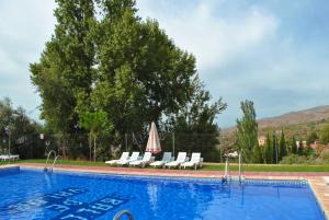 a swimming pool with white chairs and a umbrella at Casa Número 1 in Válor