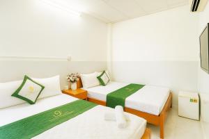 two beds in a room with white walls at Thanh Long Hotel Hồ Chí Minh in Ho Chi Minh City