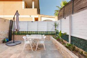 a patio with a table and chairs and an umbrella at La historia de la Casa de los Gatos in Los Narejos