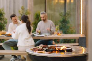 un groupe de personnes assises à une table avec un grill dans l'établissement Woodz Lodges - Unwind in nature, à Bolderberg