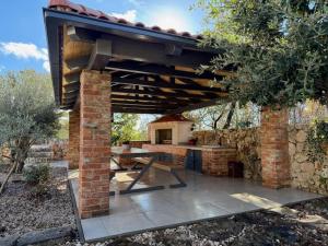 an outdoor kitchen with a wooden roof and a stone wall at Villa Posija in Kras
