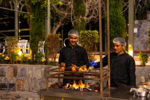 two men are cooking food on a grill at Granny's Den BY ELIVAAS in Dhanaulti