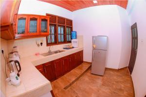 eine Küche mit Edelstahlkühlschrank und Holzschränken in der Unterkunft Peacock Hill Villa in Matugama