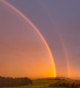 a double rainbow in the sky at sunset at Mountain Pure Lodge in Gore