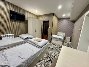 une chambre avec deux lits et une télévision au mur dans l'établissement Amiriy hostel, à Boukhara