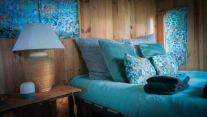 a bedroom with a blue bed with a lamp and pillows at Chambre d'hôtes Sous Les Grands Chênes Cabane du CHENE in Saint-Étienne-de-Corcoué