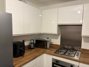 La cuisine est équipée de placards blancs, d'une cuisinière et d'un four micro-ondes. dans l'établissement Bettys Acklam hideout, à Middlesbrough