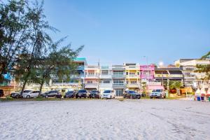 um parque de estacionamento com carros estacionados em frente aos edifícios em Coral Beach House Rayong em Ban Noen Phra