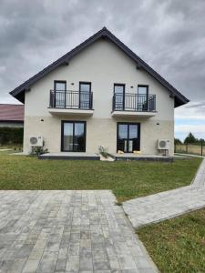 a white house with black windows and a yard at Rewal Komfortowy Apartament 2 Sypialnie 10 min od Plaży Parking Taras Grill in Rewal