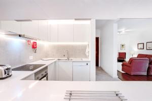 a kitchen with white cabinets and a red chair at GuestReady - Casa do Visconde in Rosto de Cão +49 photos