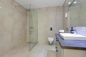 a bathroom with a shower and a sink and a toilet at Bright and Spacious Condo Downtown in Reykjavík +25 photos