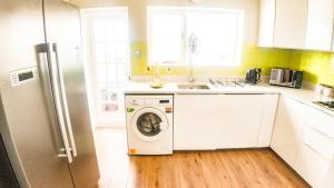 a kitchen with a washing machine in a white kitchen at Stunning 5 Bedroom House in London - Sleeps up to 10 guests - Business - Contractors - Families - Leisure - WiFi - Parking - Garden in Grove Park