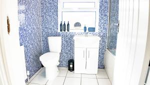 a blue tiled bathroom with a toilet and a sink at Stunning 5 Bedroom House in London - Sleeps up to 10 guests - Business - Contractors - Families - Leisure - WiFi - Parking - Garden in Grove Park