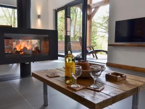 a living room with a fireplace and a table with wine glasses at Glan-Y-Gors in Beddgelert