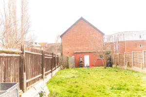 a yard with a fence and a brick building at Stunning 5 Bedroom House in London - Sleeps up to 10 guests - Business - Contractors - Families - Leisure - WiFi - Parking - Garden in Grove Park