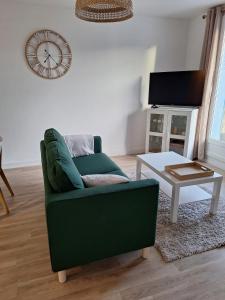 ein Wohnzimmer mit einer grünen Couch und einem Tisch in der Unterkunft T2 rénové 3ème étage places parking résidence in Manosque