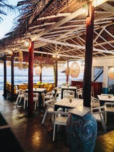a restaurant on the beach with tables and chairs at Why Not Guest house - Hikkaduwa in Hikkaduwa