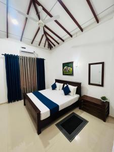 a bedroom with a bed with blue and white sheets at Yala Mangora Inn in Tissamaharama