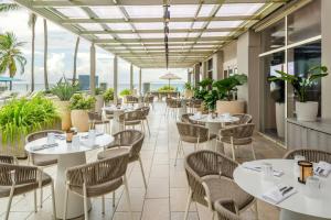 un restaurant avec des tables et des chaises blanches et des fenêtres dans l'établissement San Juan Marriott Resort and Stellaris Casino, à San Juan