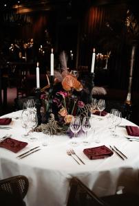 una mesa con mantel blanco con velas y copas de vino en Häckeberga Slott, en Genarp