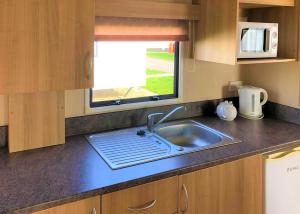 eine Küchentheke mit Spüle und Fenster in der Unterkunft Golden Anchor Caravan Park in Chapel Saint Leonards + 8 Fotos