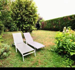 Deux chaises blanches assises dans l'herbe dans une cour dans l'établissement Maison confortable et calme, à Lens 12 autres photos