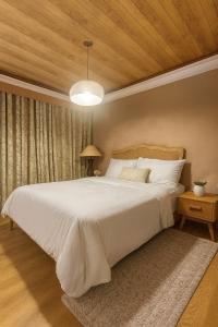a bedroom with a large white bed with a wooden ceiling at Terravive in Manila