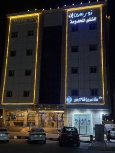 un bâtiment avec des voitures garées devant lui la nuit dans l'établissement شقق نورسين ان للشقق المخدومة, à Quai