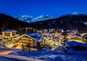ein Resort im Schnee bei Nacht mit schneebedeckten Bergen in der Unterkunft VACANZE VICINO ALLE PISTE - Vicino a Parcheggio e Centro Benessere - Parco Naturale Adamello Brenta - WI-FI & Netflix in Caderzone