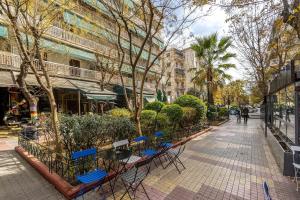 eine Straße mit Stühlen und einem Tisch auf dem Bürgersteig in der Unterkunft Athens Lodge in Koukaki in Athen