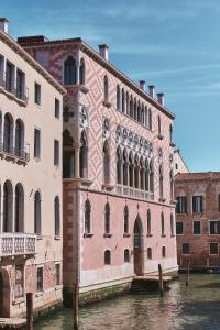 a large pink building next to a canal at Orient Express Venezia in Venice