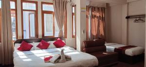 a bedroom with a bed with red pillows and a chair at Hotel Silver Jubilee in Kathmandu +59 photos
