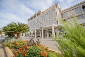a large building with flowers in front of it at Hotel Korkyra in Vela Luka