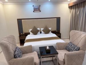 une chambre d'hôtel avec un lit et deux chaises dans l'établissement شقق نورسين ان للشقق المخدومة, à Quai