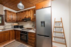 a kitchen with wooden cabinets and a stainless steel refrigerator at Dandy Villas Tsagkarada - Sky Blue Pansy - Jacuzzi in Tsagarada