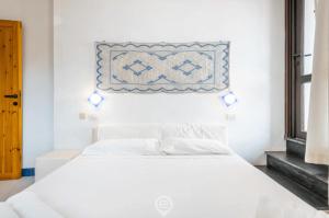 Una cama blanca en una habitación blanca con una foto en la pared en Waterside Oasis House, en Villasimius