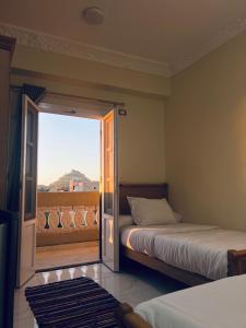 a bedroom with two beds and a door to a balcony at RAAK HOTEL فندق راك in Siwa