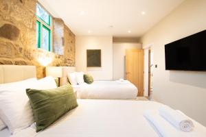 a bedroom with two beds and a flat screen tv at Northern Hideaways The Old Chapel, Otterburn in Otterburn +111 photos