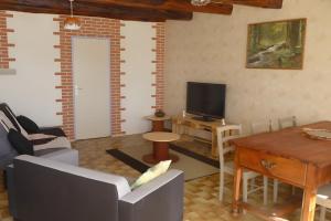 a living room with a couch and a tv at Gite les Magnans in Teillet