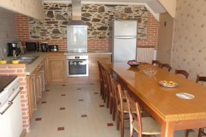 a kitchen with a long wooden table and a refrigerator at Gite les Magnans in Teillet +23 photos