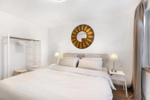 ein weißes Schlafzimmer mit einem großen Bett und einem Spiegel in der Unterkunft Ferienwohnung Im Laubgarten in Öhningen
