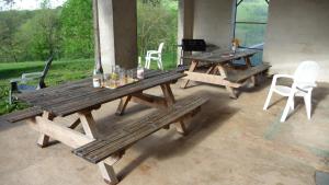 two wooden picnic tables and chairs on a patio at Gite les Magnans in Teillet