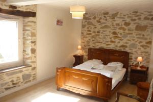 a bedroom with a bed and a stone wall at Gite les Magnans in Teillet