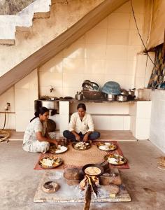 Ein Mann und eine Frau sitzen in einer Küche und bereiten Essen zu. in der Unterkunft Ahluwalias Farmstay in Mandlā