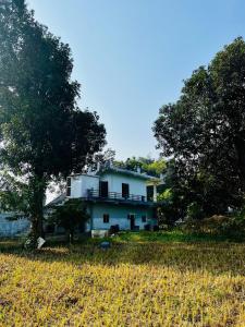 ein weißes Haus auf einem Feld mit Bäumen in der Unterkunft Ahluwalias Farmstay in Mandlā