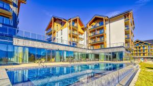 an external view of a building with a swimming pool at Mountain Horizon Valley z basenami, saunami i strefą fitness by Royal Aparts in Szklarska Poręba