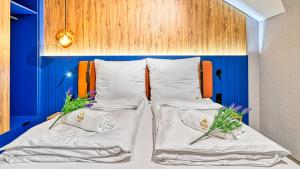 two beds in a room with blue walls and flowers at Mountain Horizon Valley z basenami, saunami i strefą fitness by Royal Aparts in Szklarska Poręba